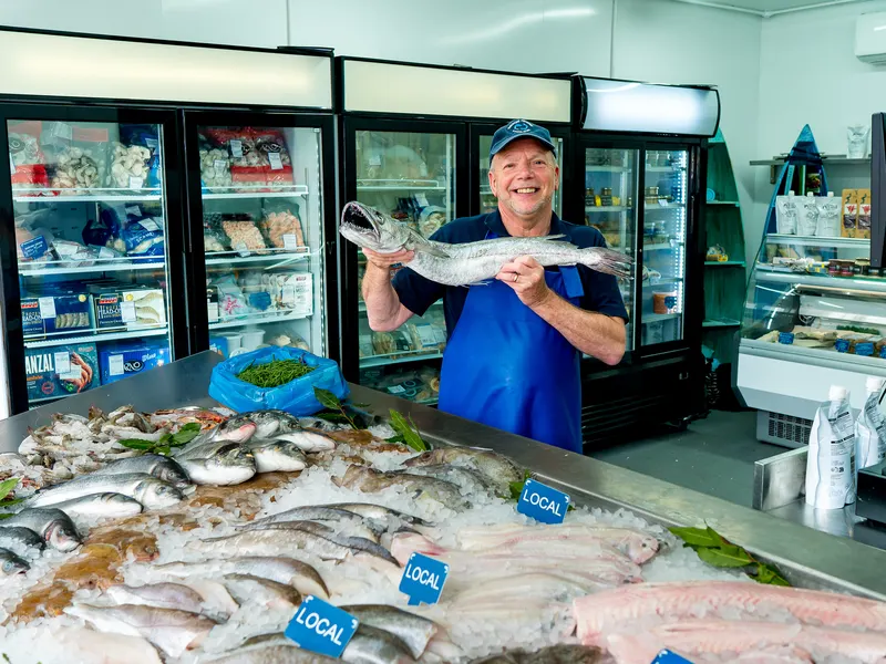 Steve holding a fresh fish behind the counter