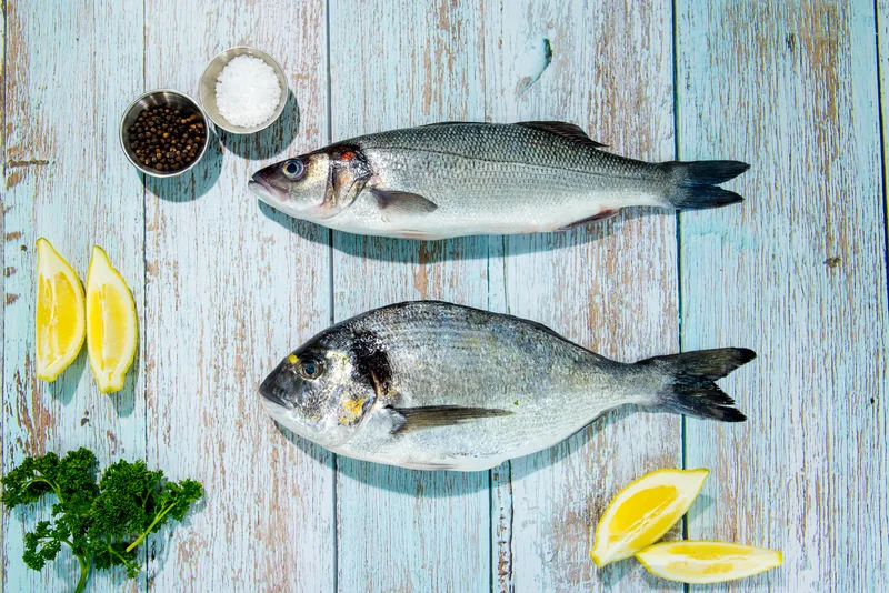 A whole bass and a whole bream with lemon, parsley, sea salt and peppercorns