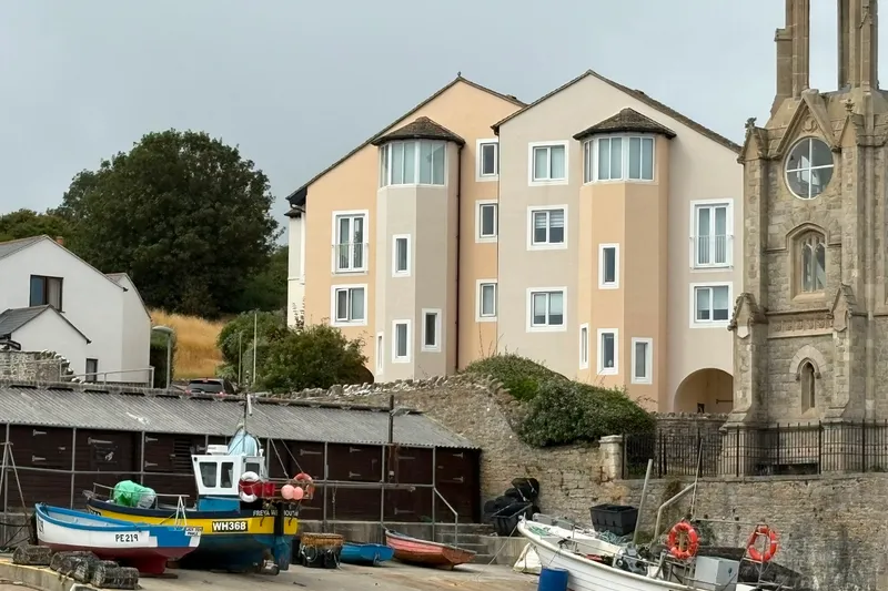 Small inshore fishing boats hauled up on a harbour slipway beside a stone clock tower